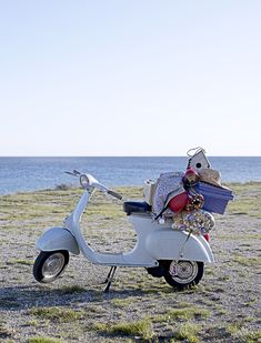 a scooter is parked on the beach with some items piled on top of it