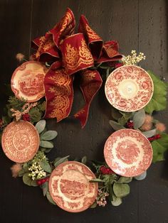 a wreath made out of plates with red and gold designs on it, hanging from the wall