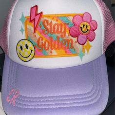 a purple and white trucker hat with an embellished flower on the front