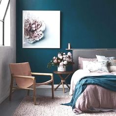 a bedroom with teal walls and white bedding, two chairs in front of the bed