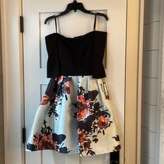 a dress hanging up on a door with a black top and floral print skirt underneath it