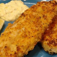 two pieces of fish on a blue plate with lemon wedges and mayonnaise