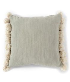 a light green pillow with white pom - poms