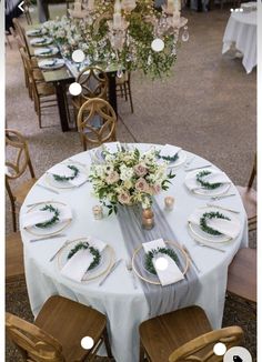 the table is set with white linens and greenery