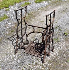 an old metal chair sitting on top of a gravel road