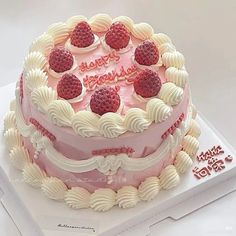 a birthday cake decorated with raspberries and frosting