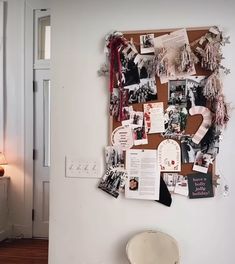 a bulletin board covered in pictures and other items next to a lamp on a wall