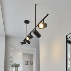 three lights are hanging from the ceiling in a room with white walls and flooring