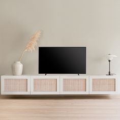 a flat screen tv sitting on top of a white entertainment center next to a lamp