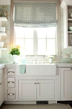 a white kitchen sink sitting under a window next to a stove top oven and cabinets