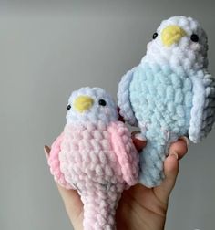 two small crocheted birds sitting on top of each other in their human's hands