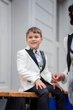 Elevate your child's style with the Radiant White Boy's Tuxedo, a charismatic choice designed to stand out. Combining impeccable taste with effortless elegance, this tuxedo ensures your little one leaves an unforgettable, dapper impression on any occasion. From HolloMen Spring Summer Collection. Tuxedo Color: White. Available sizes are from 5 to 14 years boys. It is expertly crafted from a luxurious blend of 55% Cotton and 45% Polyester. This suit is a Slim fit for a tailored look, and it features a Double slit, Single Button, and Full Lining seamlessly integrated for a sleek design. To maintain the premium quality of your Black Tuxedo Suit, dry clean only. Classic White Sets For Black Tie Occasions, White Custom Fit Tuxedo For Groom, Custom Fit White Tuxedo For Groom, White Fitted Sets For Black Tie Occasion, White Notch Lapel Tuxedo With Custom Fit, White Custom Fit Tuxedo With Notch Lapel, White Custom Fit Notch Lapel Tuxedo, White Notch Lapel Tuxedo, Custom Fit White Tuxedo Suits