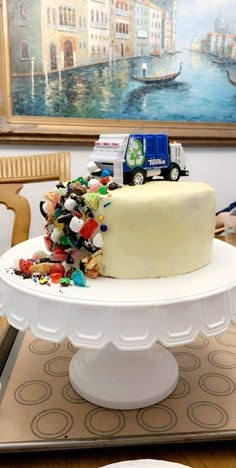 there is a cake on the table with many candies around it and a toy truck on top