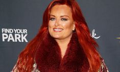 a woman with long red hair wearing a fur stoler and smiling at the camera