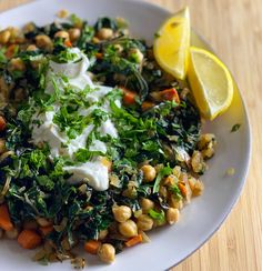 a white plate topped with lots of veggies next to a slice of lemon