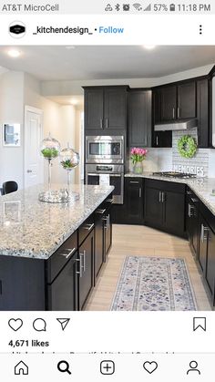 a large kitchen with black cabinets and marble counter tops, along with an area rug on the floor