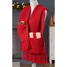 a red knitted scarf with fringes and buttons on the front, hanging from a mannequin's dummy