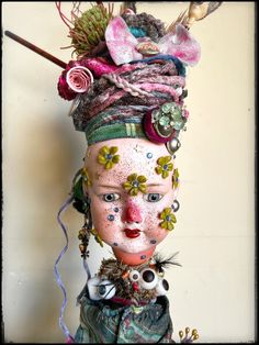 an odd looking doll with flowers on it's head and other things in her hair