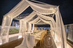 an outdoor wedding setup with white draping and string lights on the roof deck