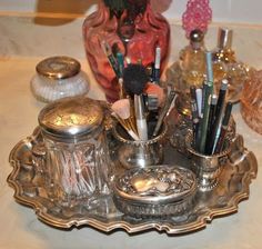 an ornate silver tray with makeup brushes and other items