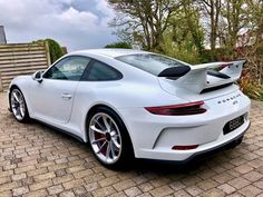 a white porsche sports car parked in front of a house