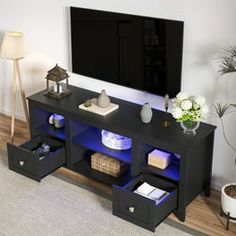 a living room with a large tv on top of a wooden shelf next to a lamp