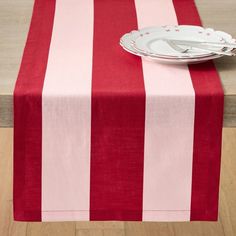 a red and white striped table cloth with silverware on the plate next to it