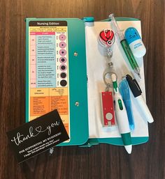 an open notebook with pens, keys and other items in it on a wooden table