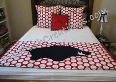 a bed with red and white polka dot sheets, pillows and a black cat on it