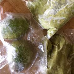 three pieces of food wrapped in plastic on top of a wooden table