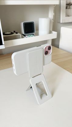 there is a cell phone holder attached to the back of an ipod stand on a table