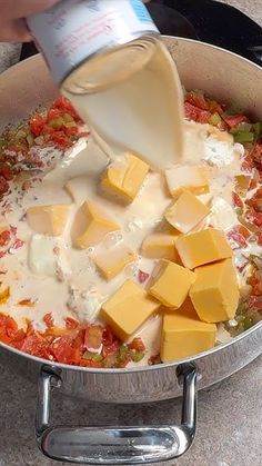 someone is pouring cheese into a pan full of food