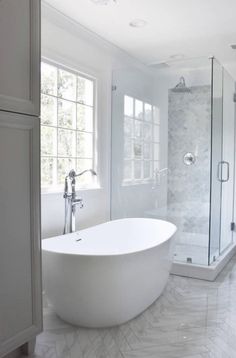 a large white bathtub sitting in the middle of a bathroom next to a walk in shower