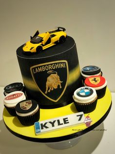 a cake with cupcakes and sports cars on the top is decorated to look like a lamb logo