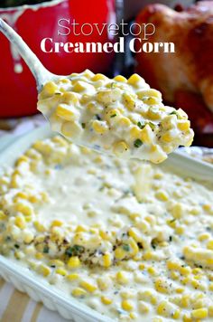 a spoon full of creamed corn on top of a casserole dish