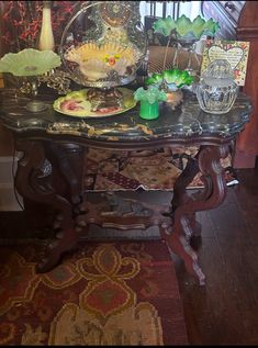 a table with plates and vases on top of it in a room filled with wood flooring