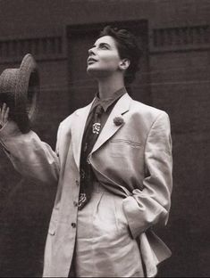 black and white photograph of a man in a suit holding up a hat with his right hand