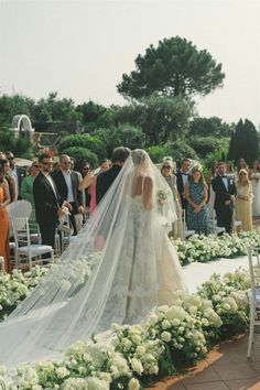 a bride walking down the aisle with her veil over her head as she walks down the aisle