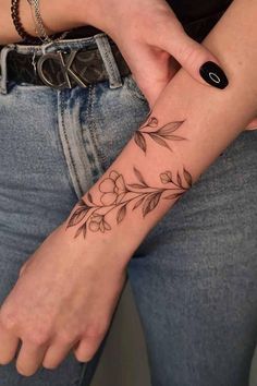 a woman's arm with a flower tattoo on the left side of her wrist