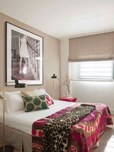 a bedroom with pink and green decor on the walls, white bedding, and wooden flooring