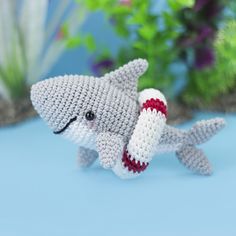 a crocheted toy shark with a red and white stripe on it's tail