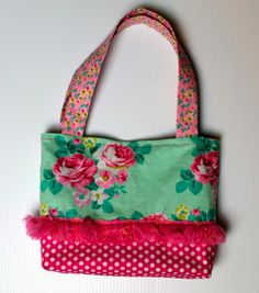 a pink and green flowered purse hanging on a white wall with polka dot dots