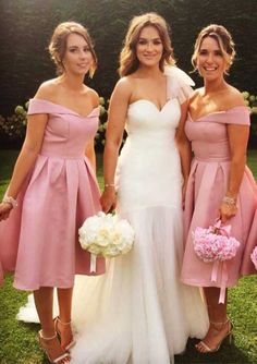 three bridesmaids in pink dresses posing for the camera and one is holding her bouquet