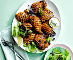 grilled chicken and cucumber salad on a white plate next to silverware