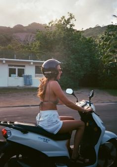 a woman riding on the back of a white scooter