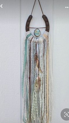 a wall hanging made out of different colored yarns and beads with a wooden hanger