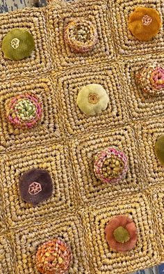 a close up of a piece of cloth with different colored buttons on it and a wooden table