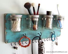 mason jars are hanging on a wall with hooks and hairbrushes attached to them