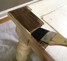 a paintbrush sitting on top of a piece of wood next to a white wall