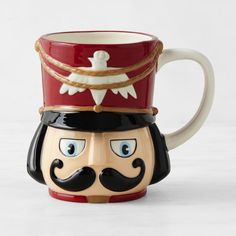 a ceramic mug with a mustache and hat on it's head, sitting in front of a white background